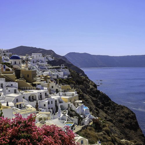 a white buildings on a cliff above water